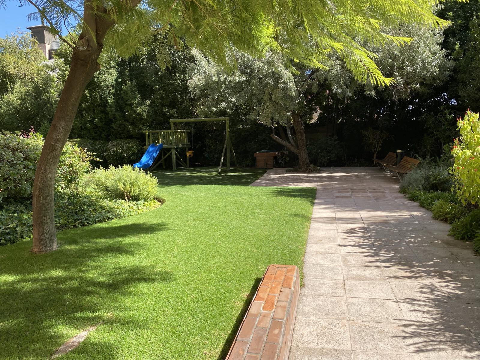 Jardín con juegos infantiles bajo los árboles